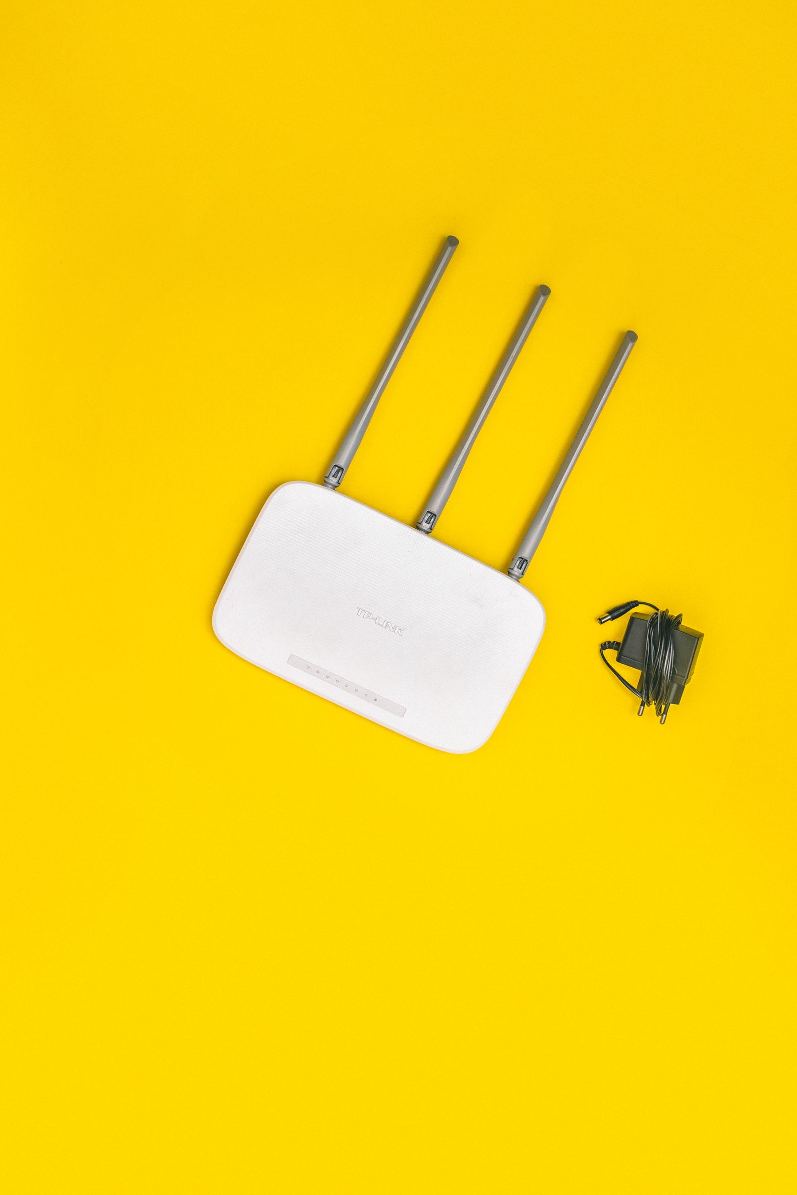 A white Wi-Fi router with antennas against a yellow background